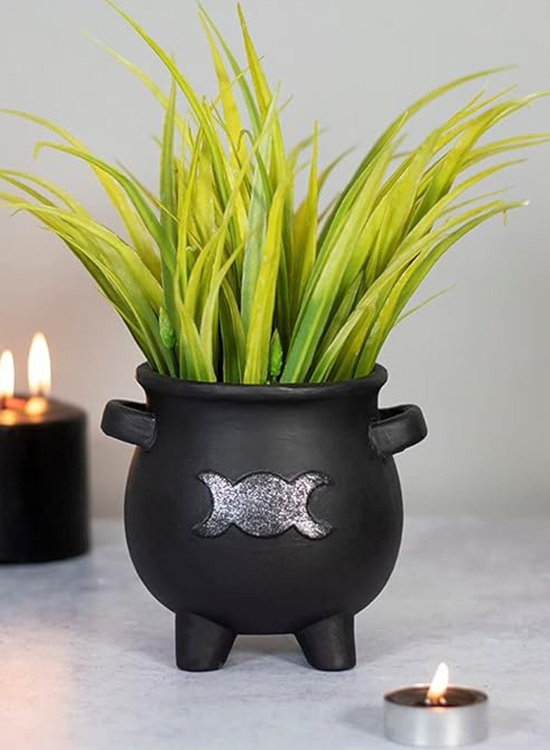 Goddess Cauldron Planter Pot - black gothic flower pot in the shape of a witch's cauldron with silver triple moon, small handles and green plants.