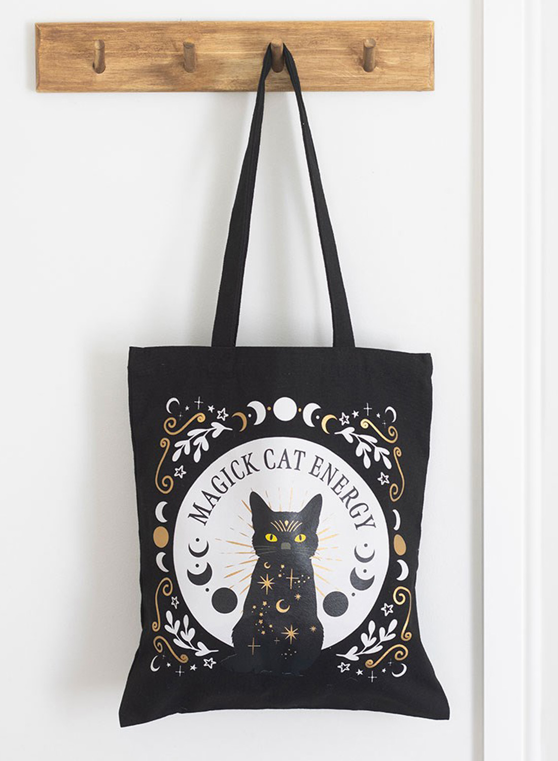 Black Magick Cat Energy Tote Bag - black fabric bag in polyester with cat motifs, yellow eyes, moon phases and stars. Dimensions 38.5 × 33.8 cm.